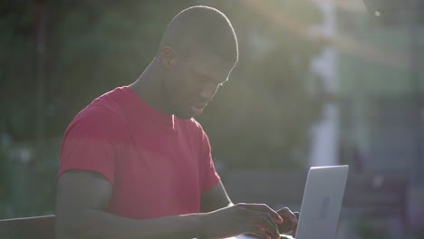 Joven-Musculoso-Afroamericano-Escribiendo-En-Una-Computadora-Portátil-En-El-Parque